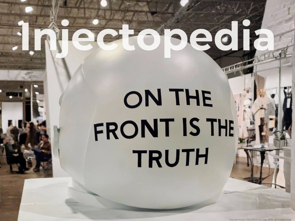 White astronaut helmet sculpture with black text reading "On the front is the truth" by artist Hayden Kays at The Other Art Fair 2019, cover of Injectopedia Issue 5 The Industry's >1% Problem